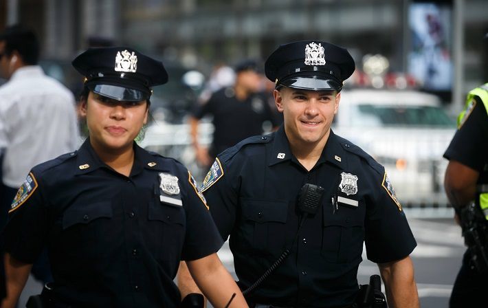 Two police officers standing next to each other on a street.