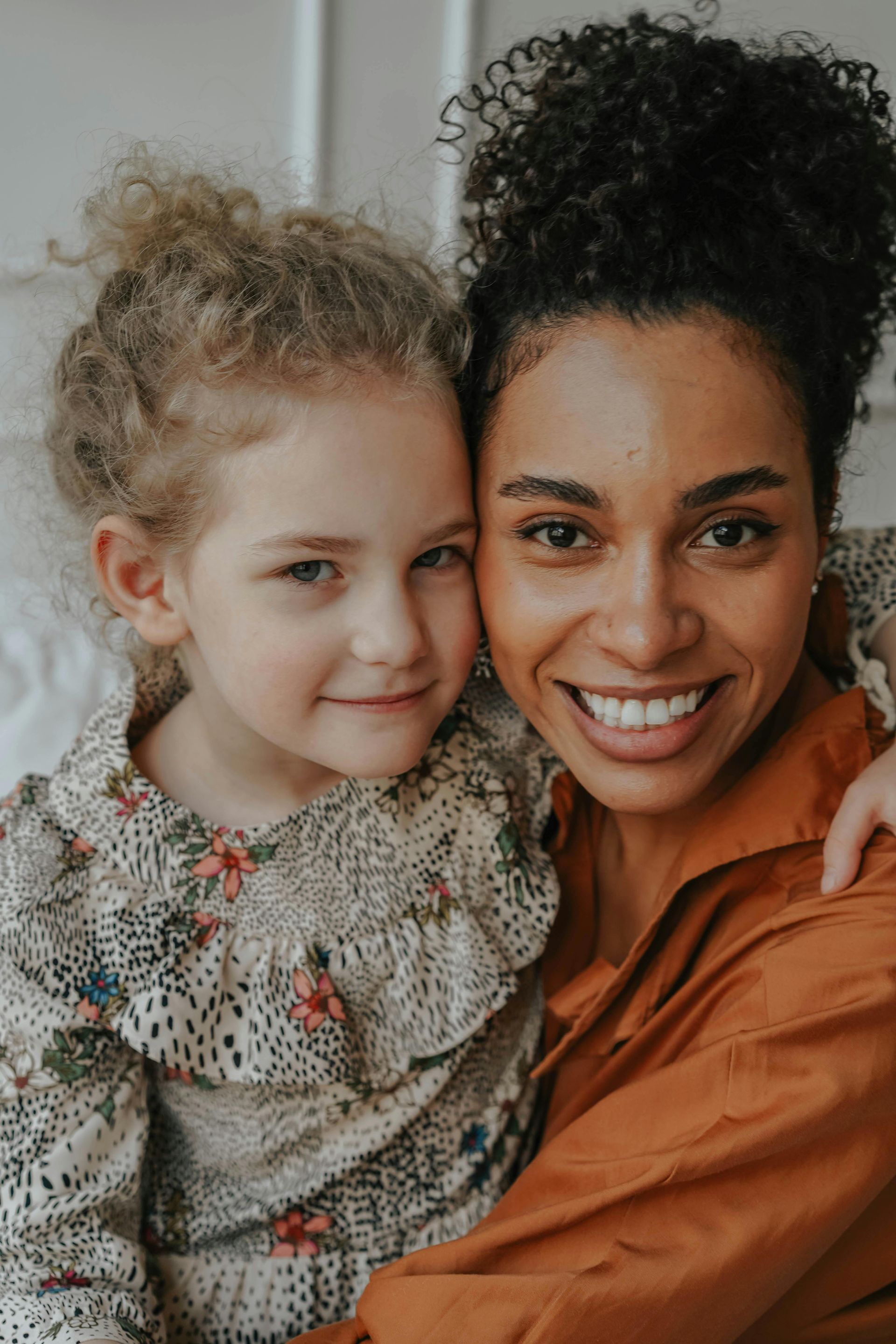 A woman is holding a little girl in her arms and they are smiling for the camera.