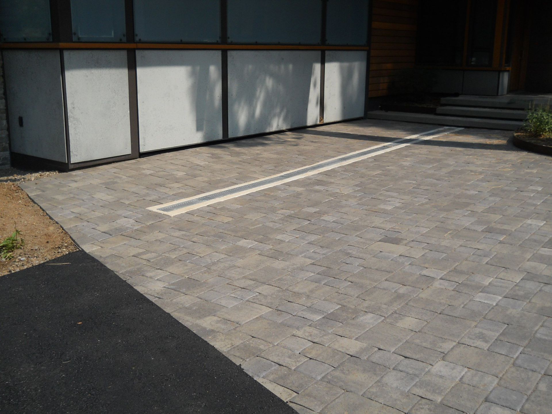 A brick driveway in front of a building with a white line on it