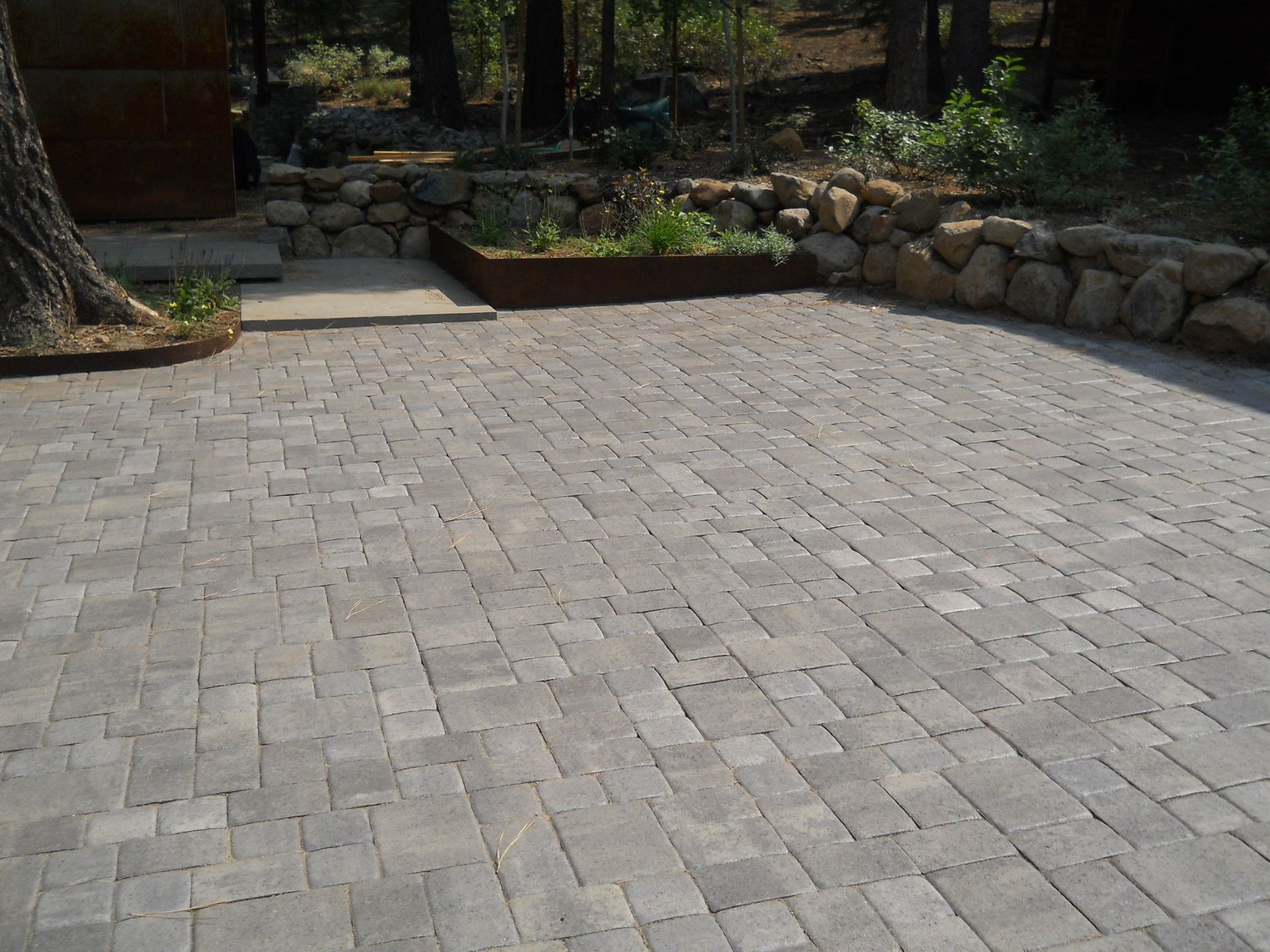 A brick driveway with a stone wall in the background