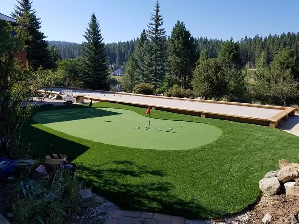 A putting green in a backyard with trees in the background