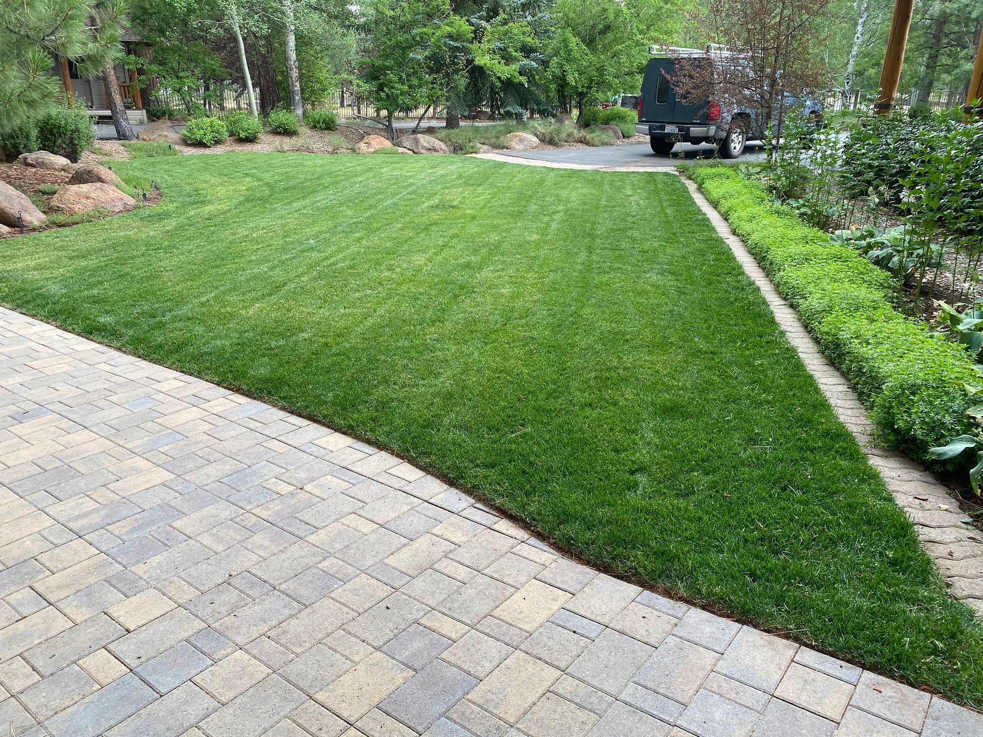 A jeep is parked in a driveway next to a lush green lawn.