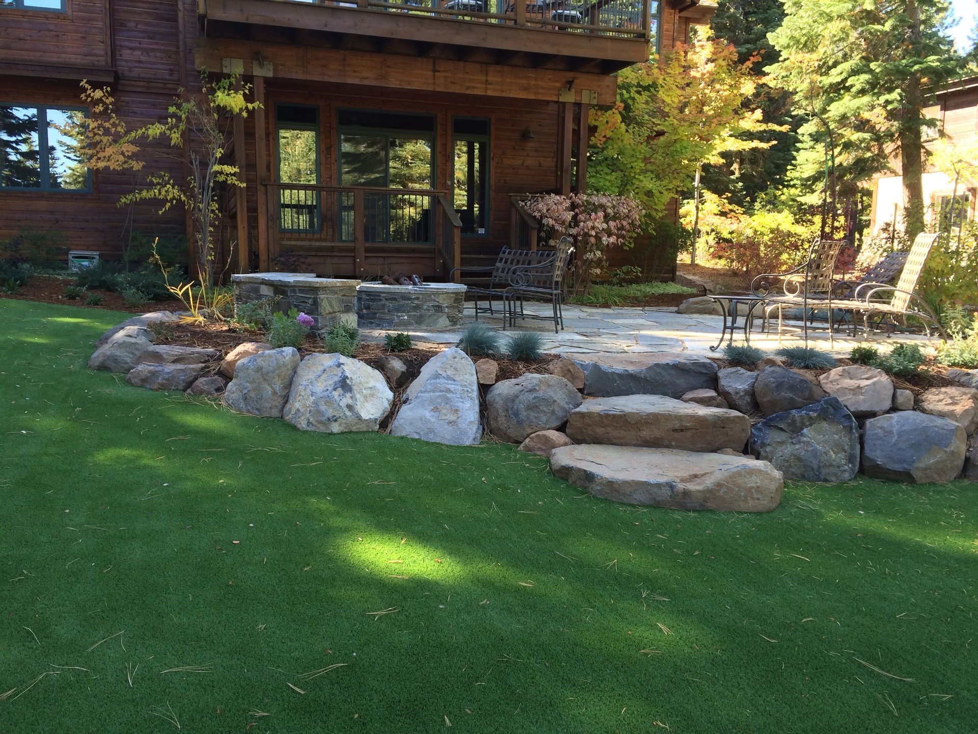 A large house with a large lawn and rocks in front of it.