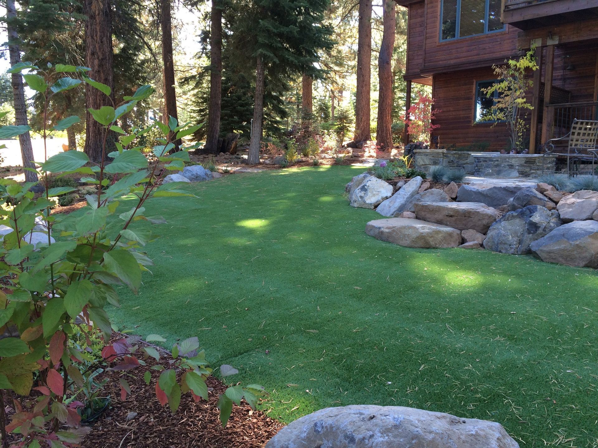 A lush green lawn with rocks and trees in the background