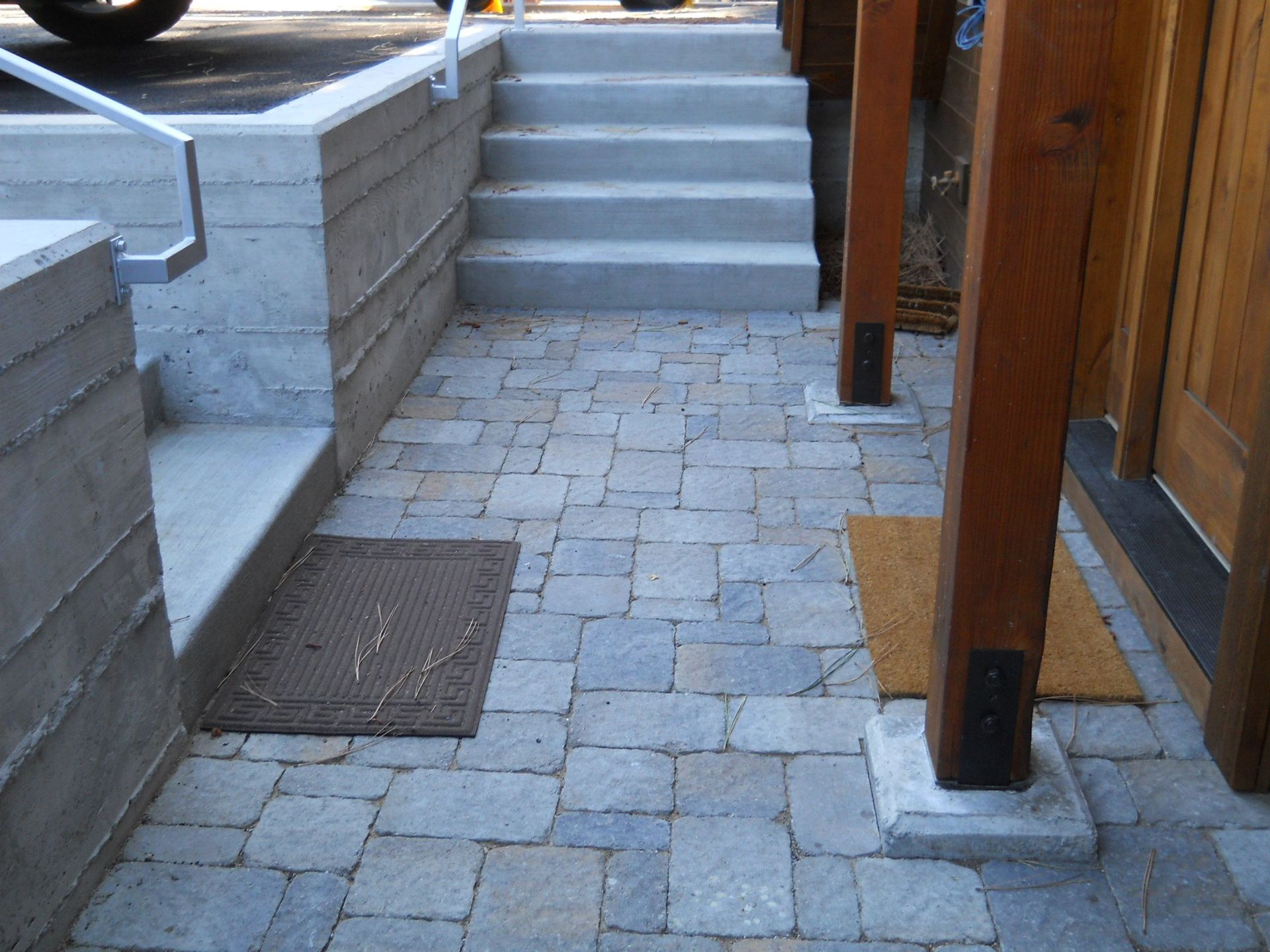 A brick walkway with stairs and a wooden post