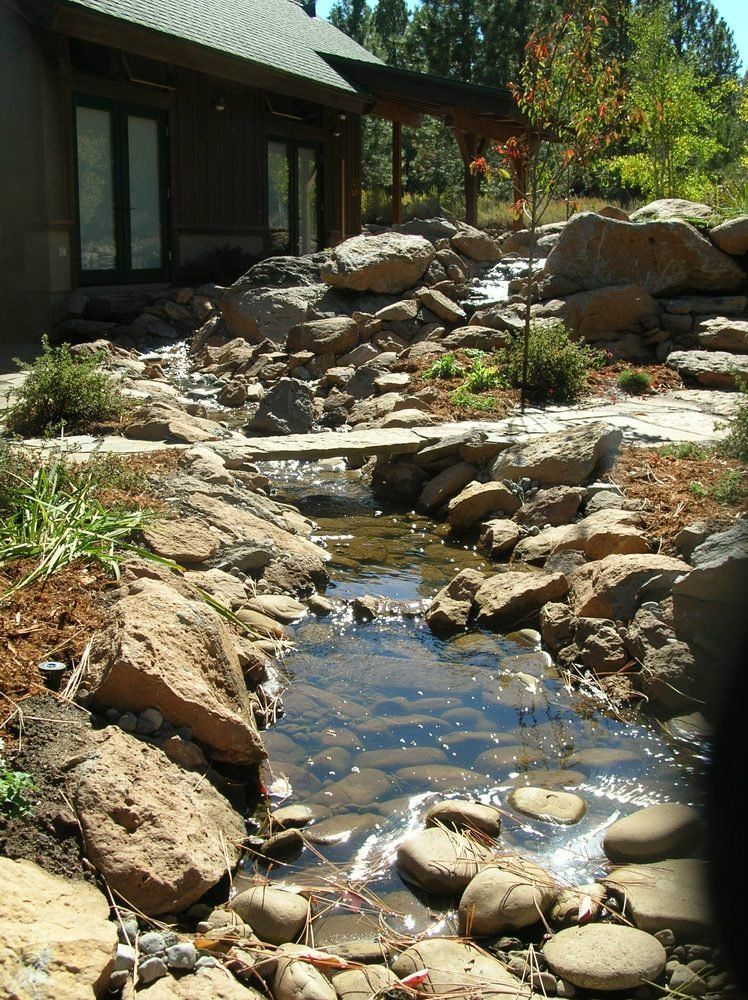 A stream running through a rocky area in front of a house