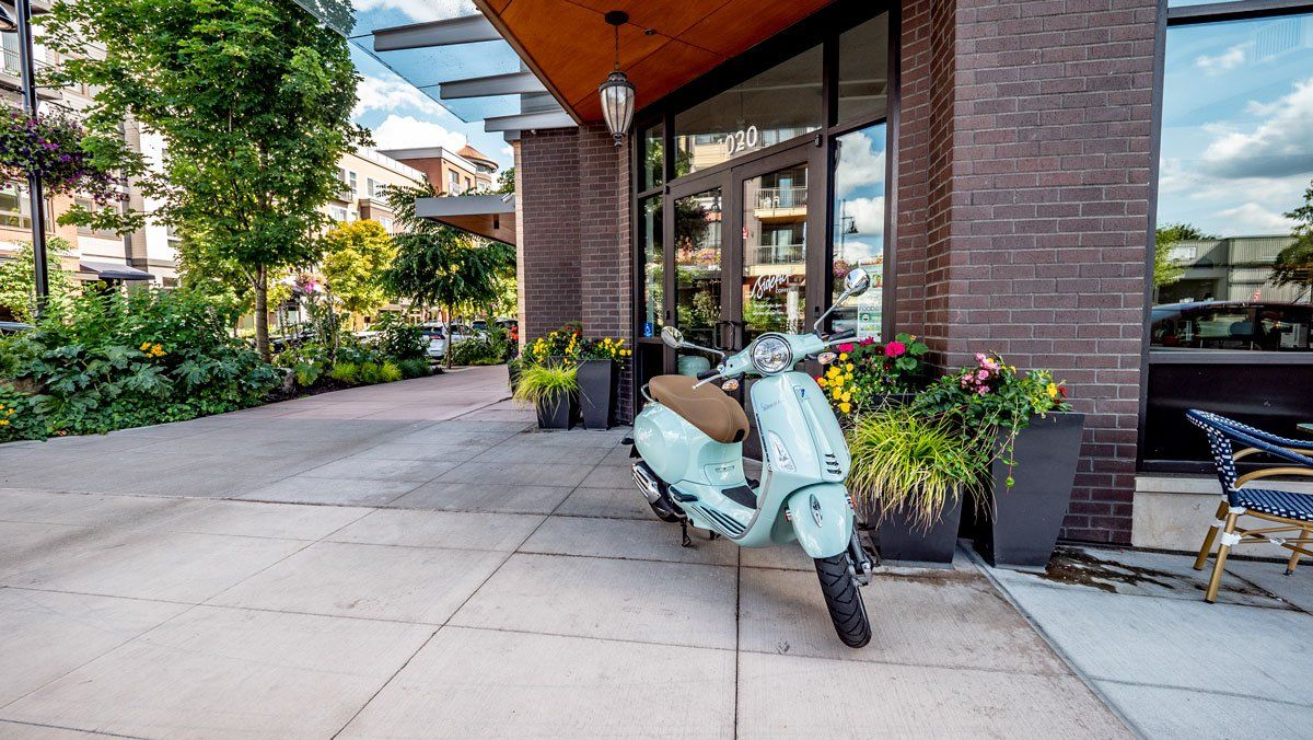 A scooter is parked on the sidewalk in front of a building.