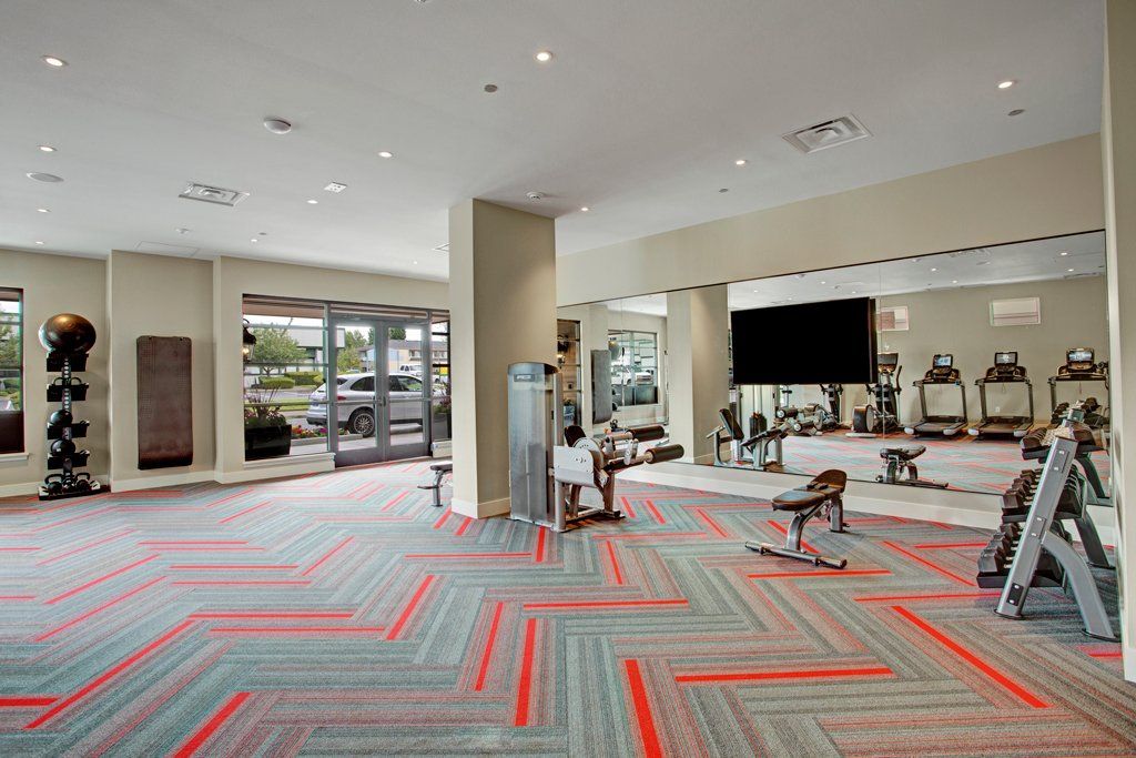A large gym with a lot of equipment and a large tv on the wall at Woodin Creek Village.