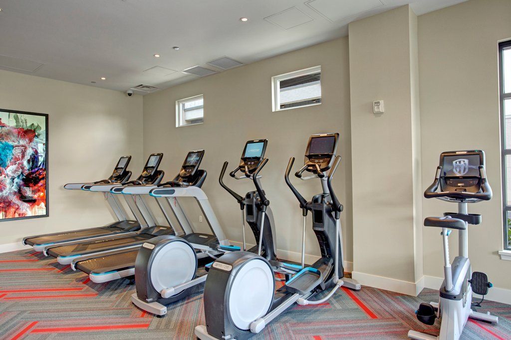 A gym with a lot of treadmills and exercise bikes at Woodin Creek Village.