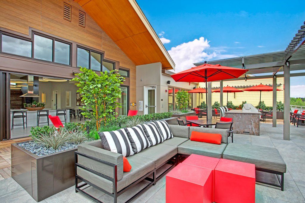 A patio with a couch and umbrellas in front of a building at Woodin Creek Village.
