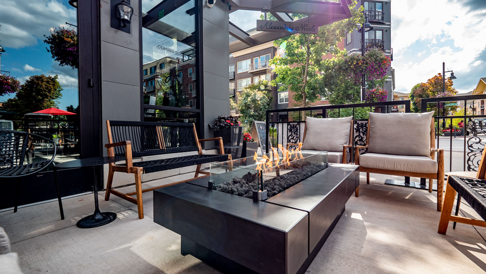 A patio with a fire pit, chairs, and a table at Woodin Creek Village.
