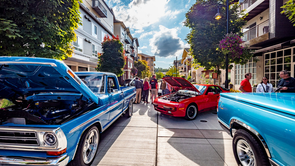 A blue truck and a red car are parked on the side of the road.
