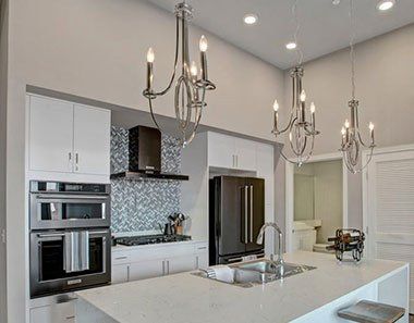 A kitchen with white cabinets, stainless steel appliances, a sink, and a refrigerator at Woodin Creek Village.