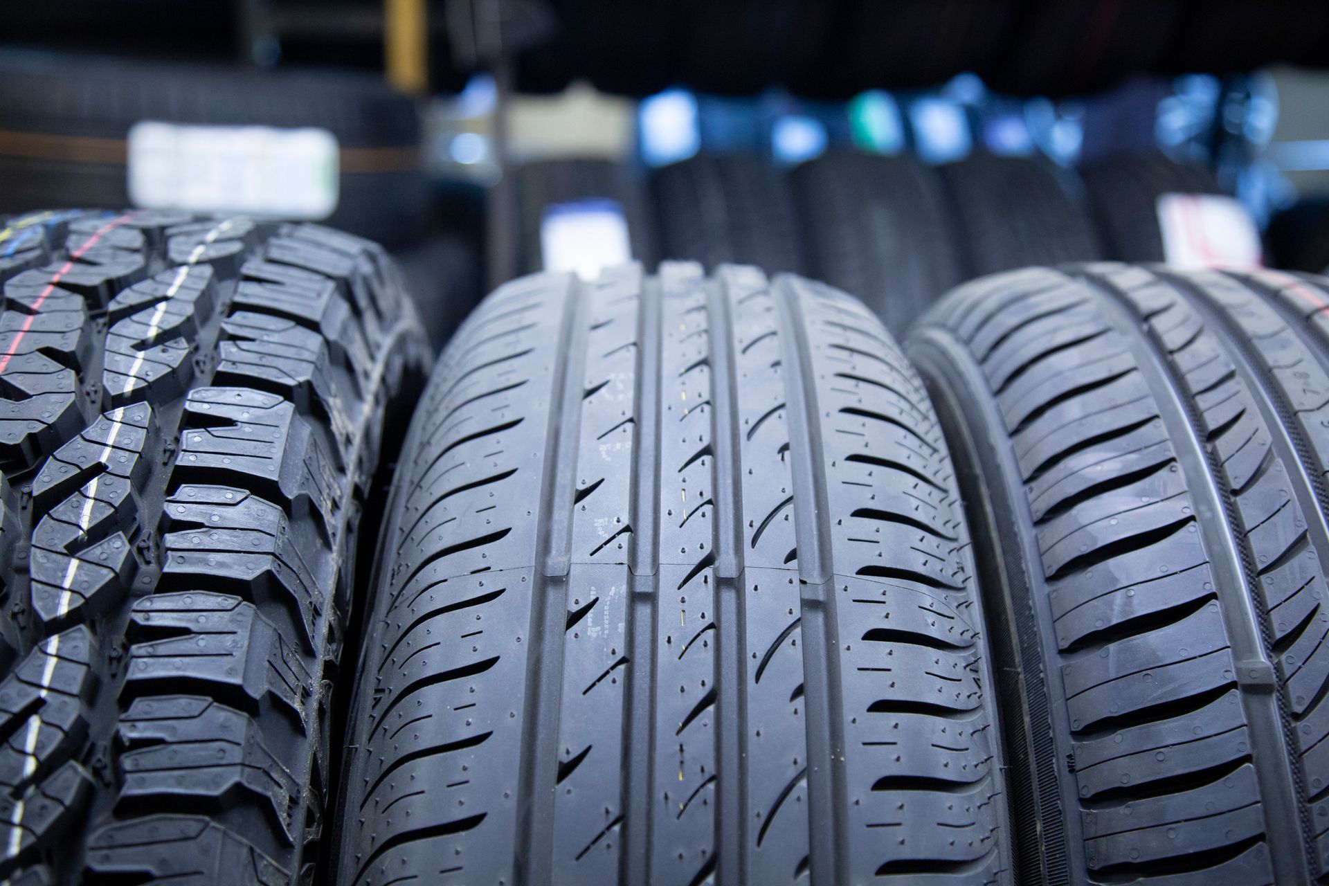Three different types of tires are lined up on a shelf.
