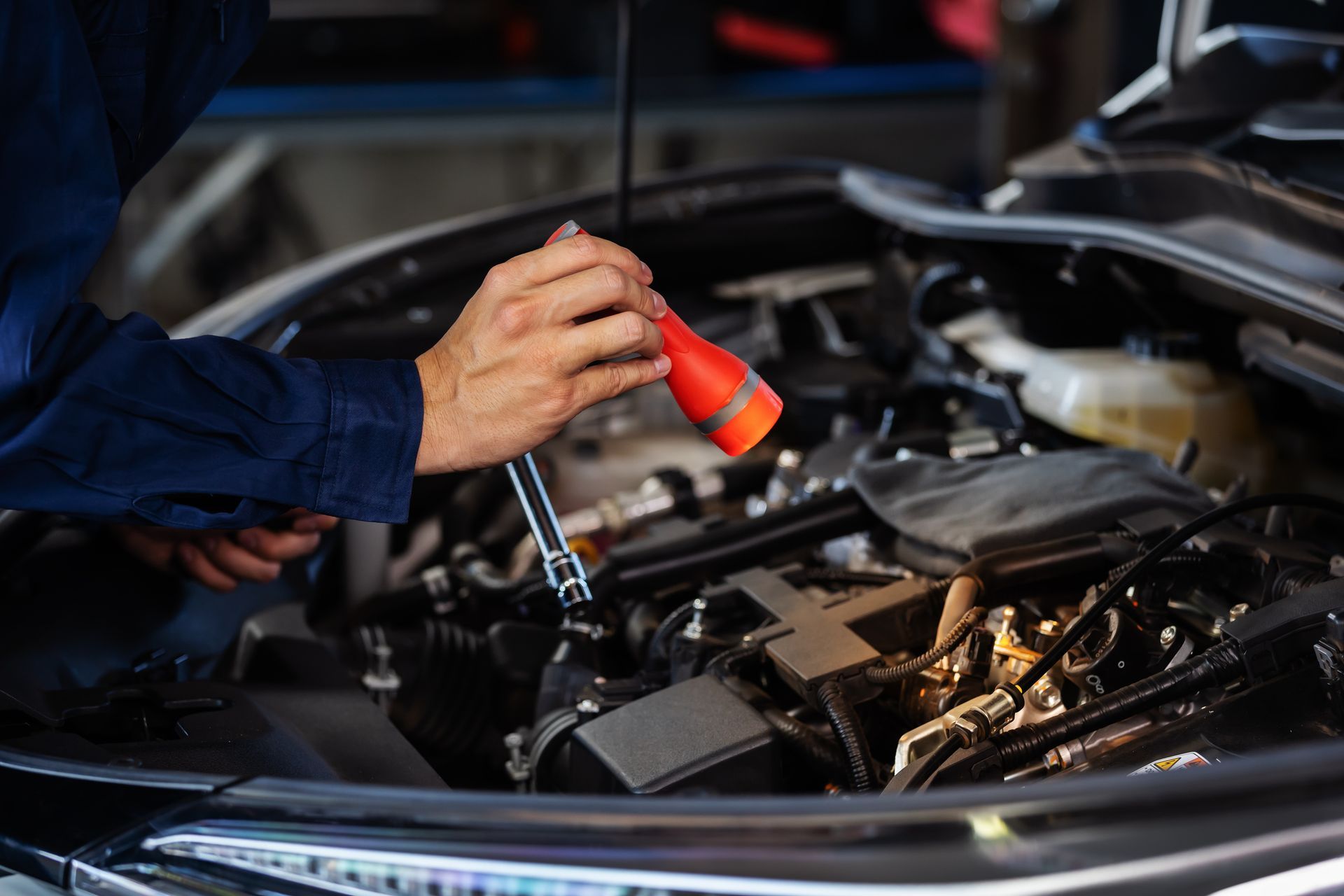 A man is working on the engine of a car with the hood open.