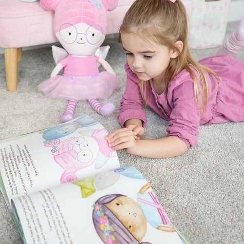 A little girl is laying on the floor reading a book.