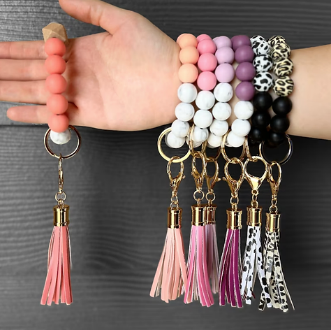 A woman is wearing a bracelet with a keychain attached to it