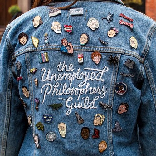 A woman is wearing a denim jacket that says the unemployed philosophers guild