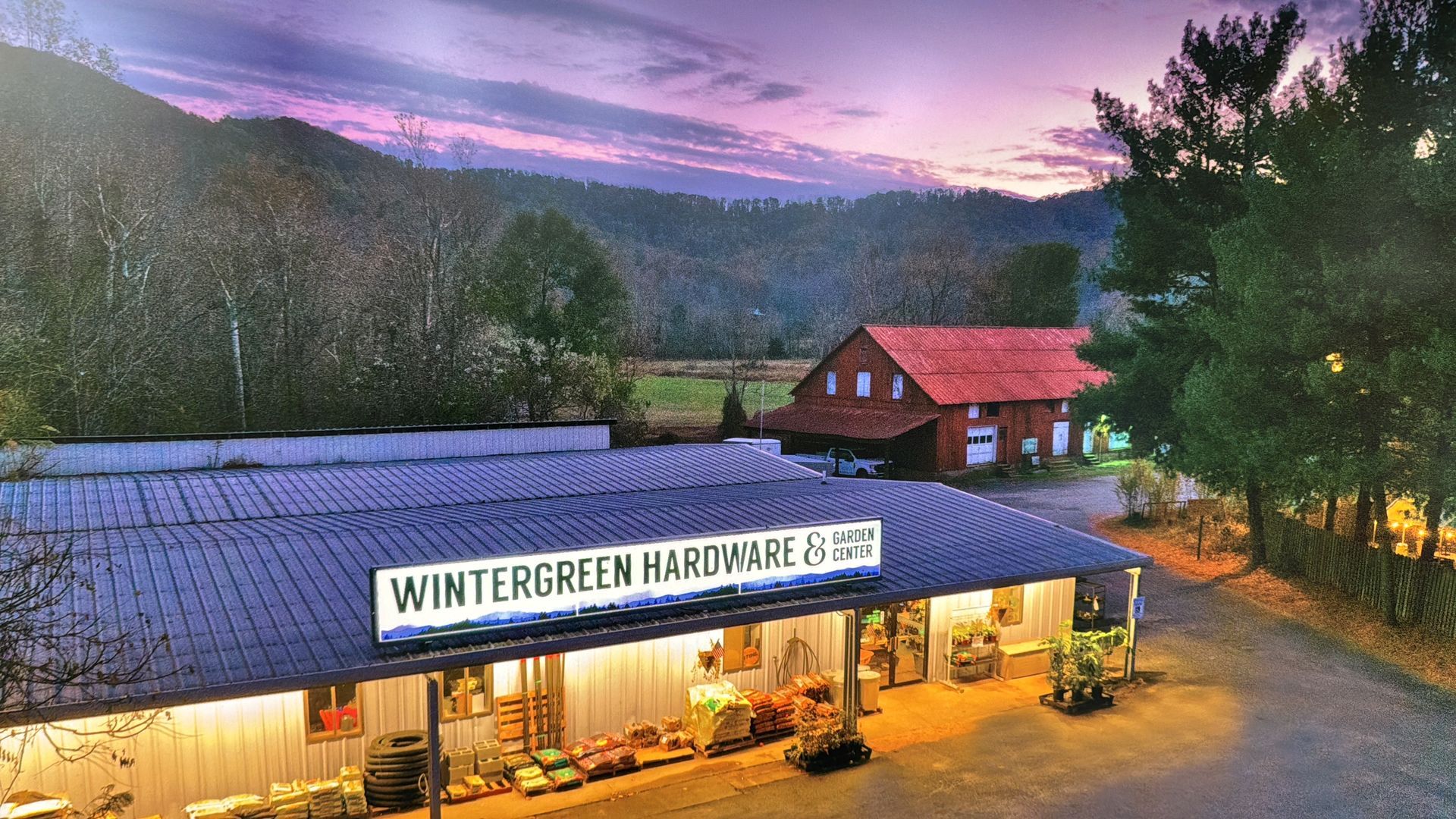 Wintergreen Hardware store with a red-roofed barn and mountains at sunset.