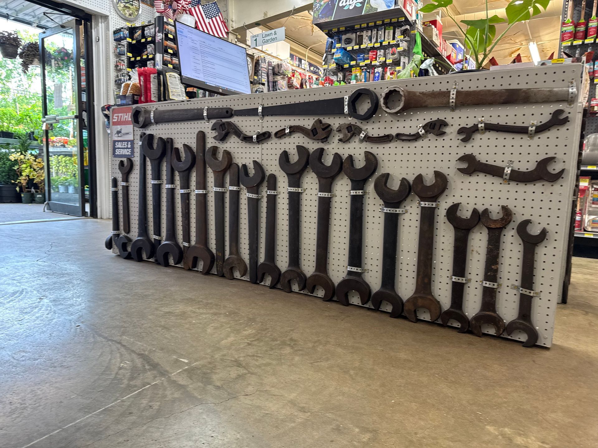 Person mowing a green lawn with a red and black lawnmower on a sunny day.