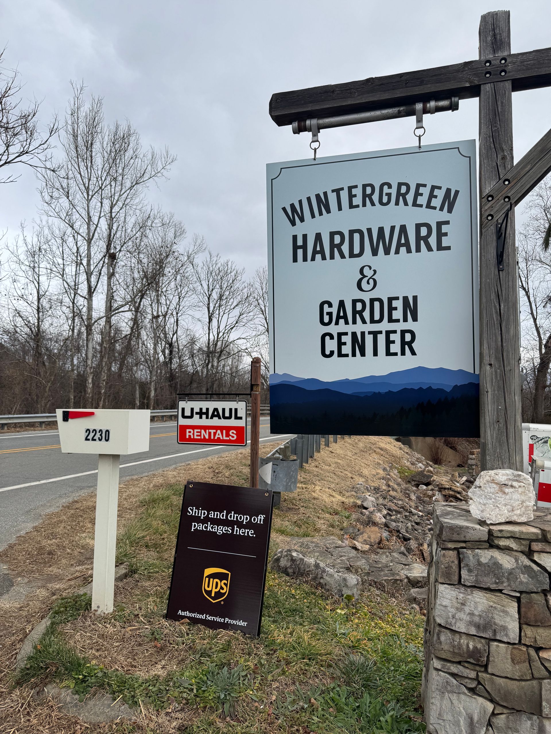 Sprinklers watering rows of lush green lettuce in a garden, with a truck and a person visible in the background.