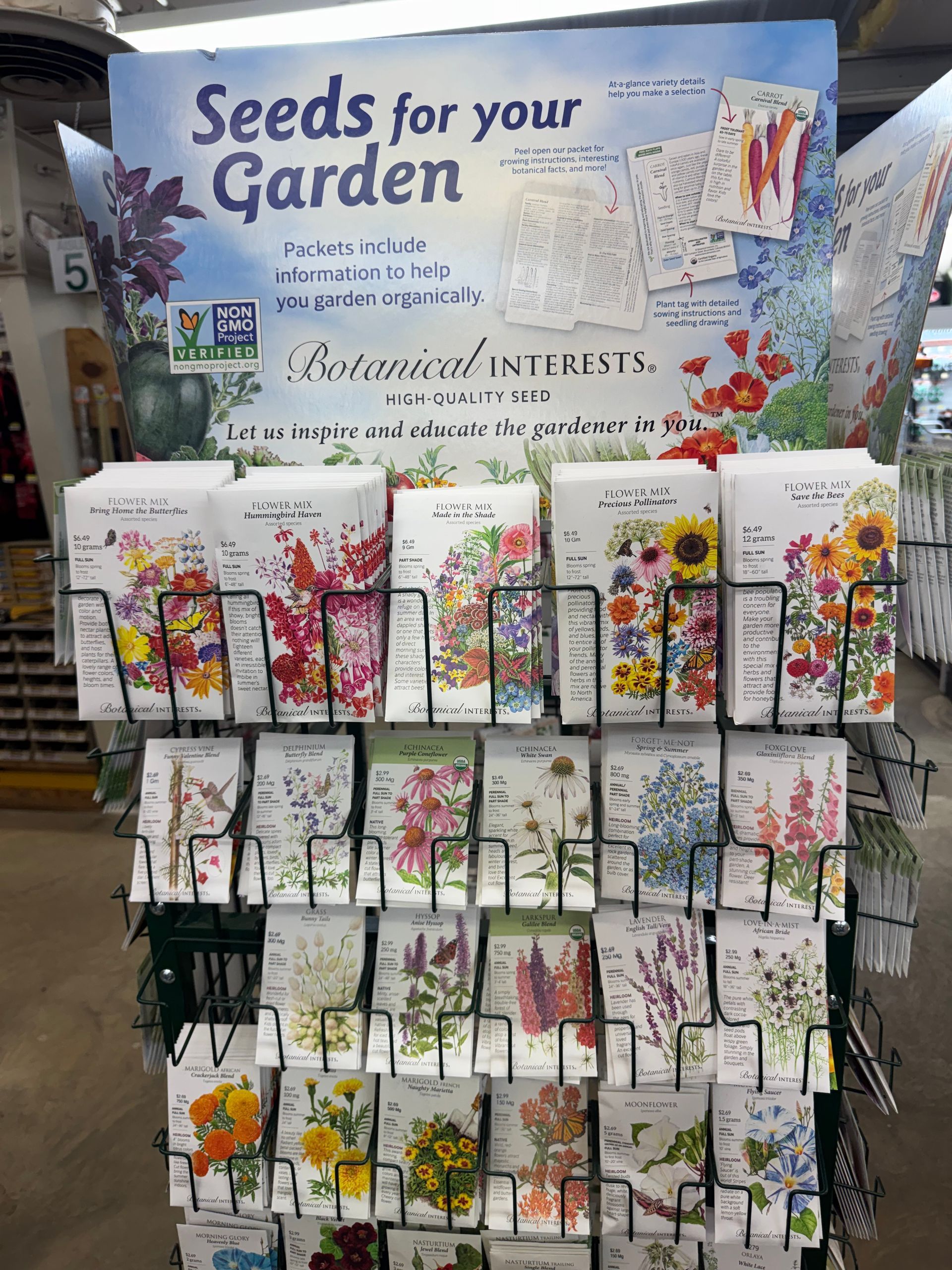 Rows of young plants in green pots inside a greenhouse.