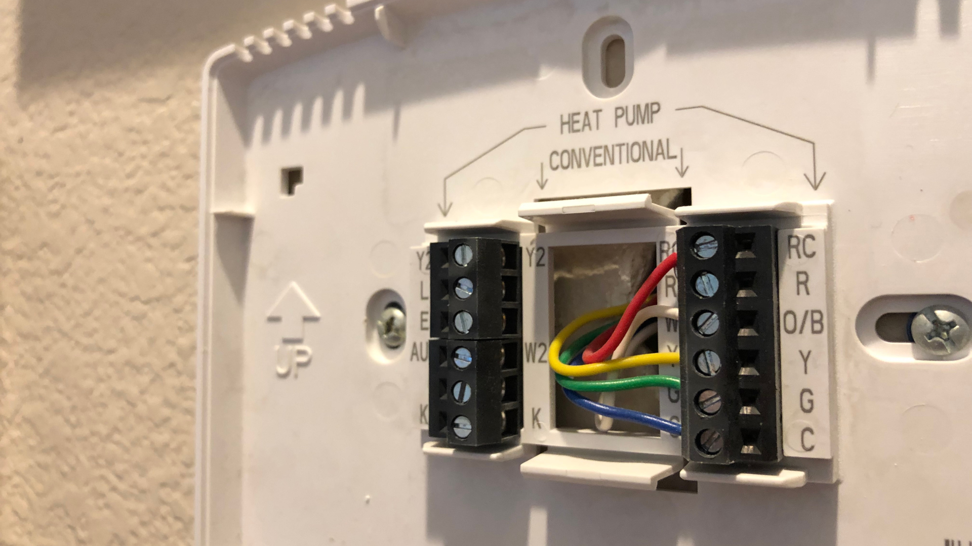 A close up of a thermostat with wires coming out of it.