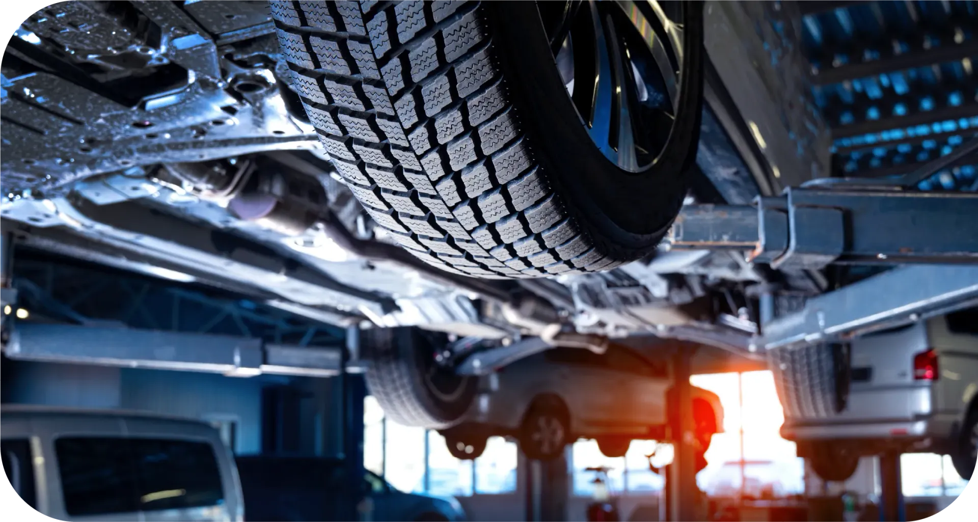 The underside of a car is being worked on in a garage.