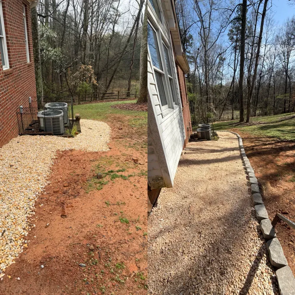 Tilted white wall panel beside a brick house, with gravel and dirt path along the side yard