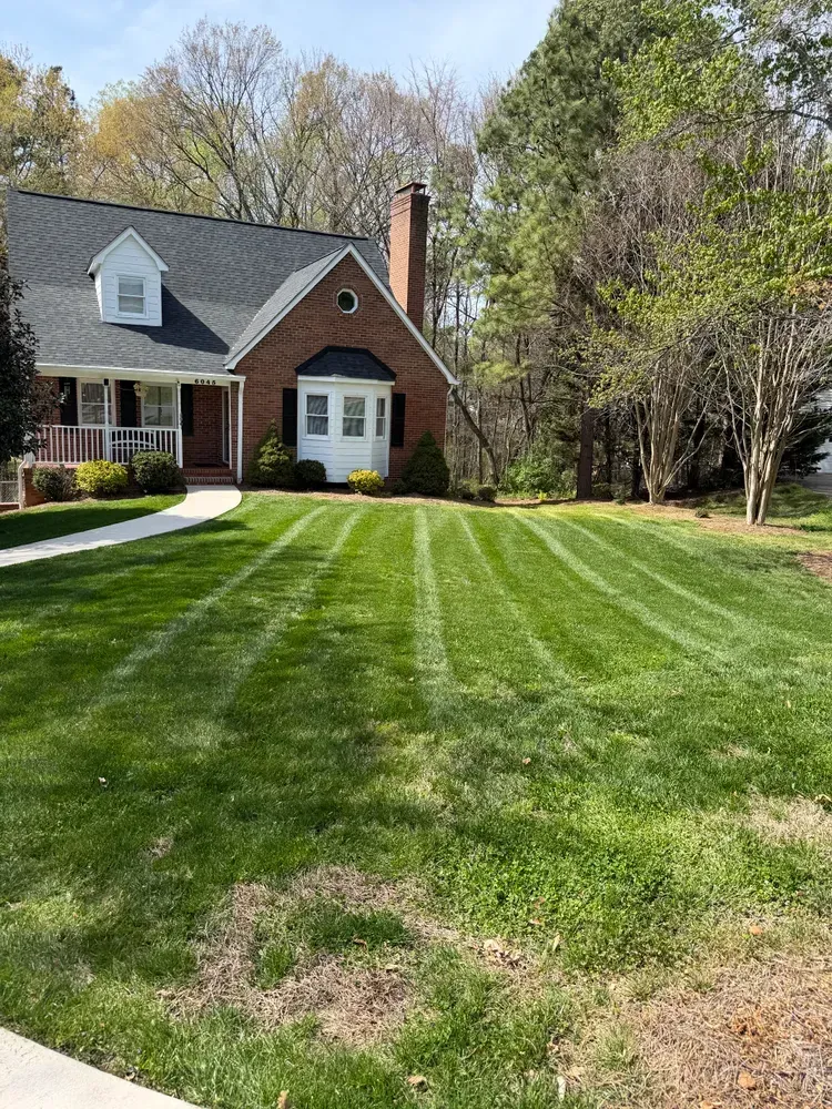 Brick house with a green lawn and trees in the yard.