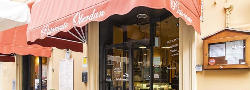 Ingresso del ristorante con tenda rossa, insegna e menù.