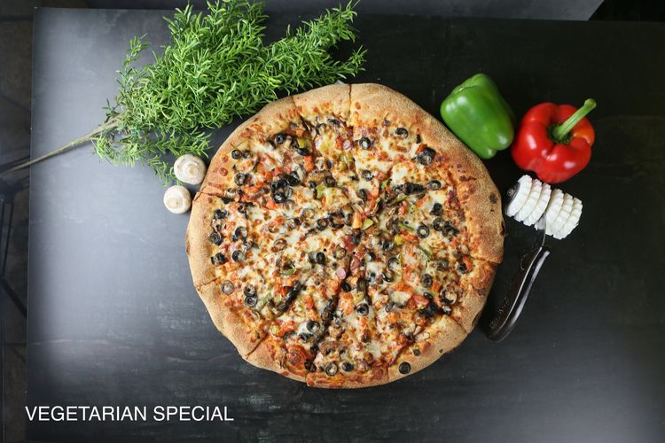 A pizza with four different toppings is sitting on a table.