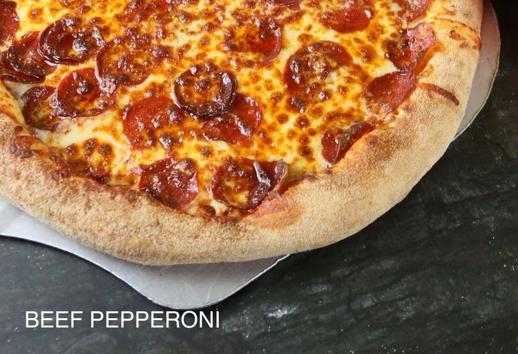 A pizza with four different toppings is sitting on a table.