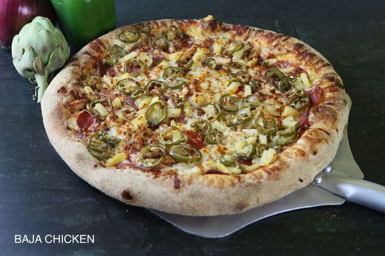 A pizza with four different toppings is sitting on a table.