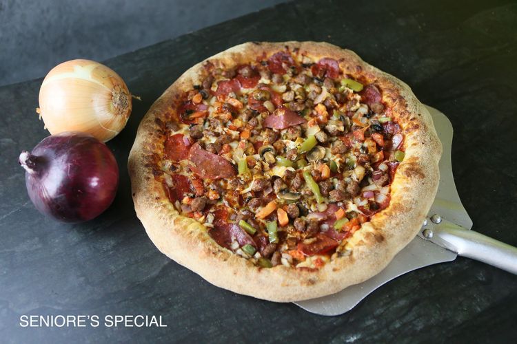 A pizza with four different toppings is sitting on a table.