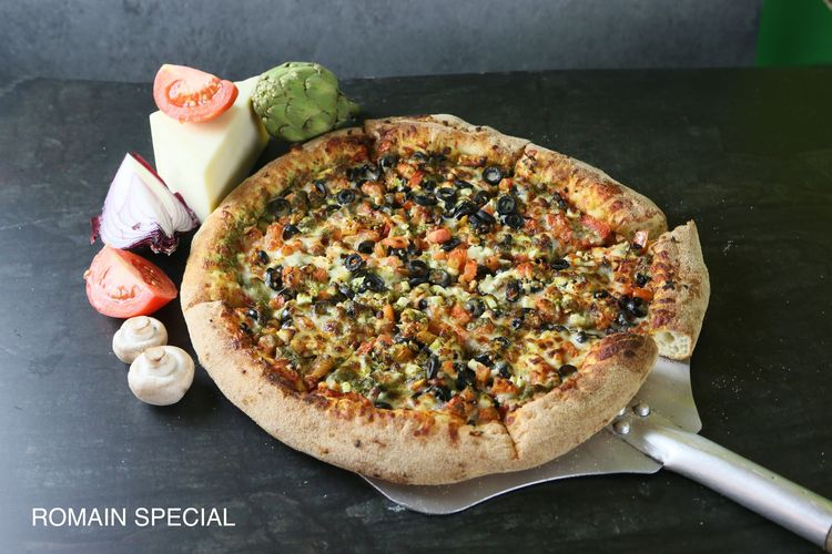 A pizza with four different toppings is sitting on a table.