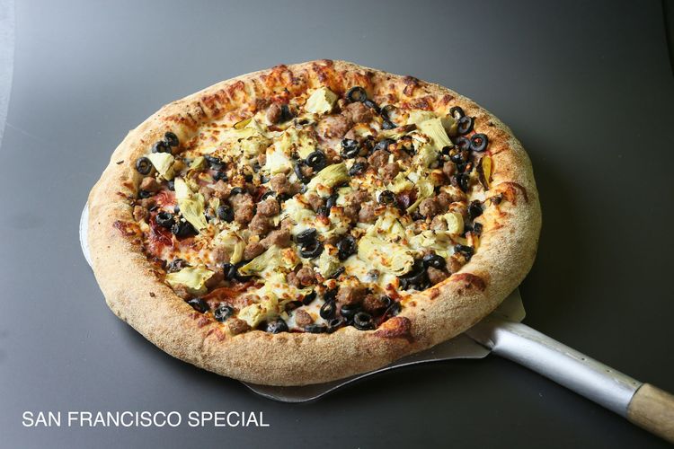 A pizza with four different toppings is sitting on a table.