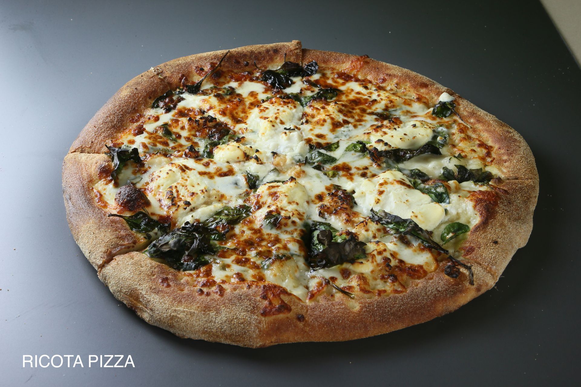 A pizza with four different toppings is sitting on a table.