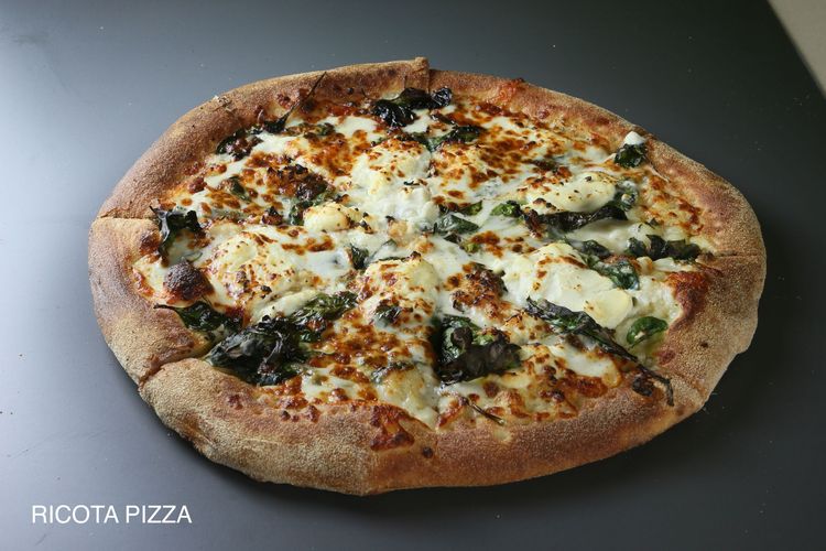 A pizza with four different toppings is sitting on a table.
