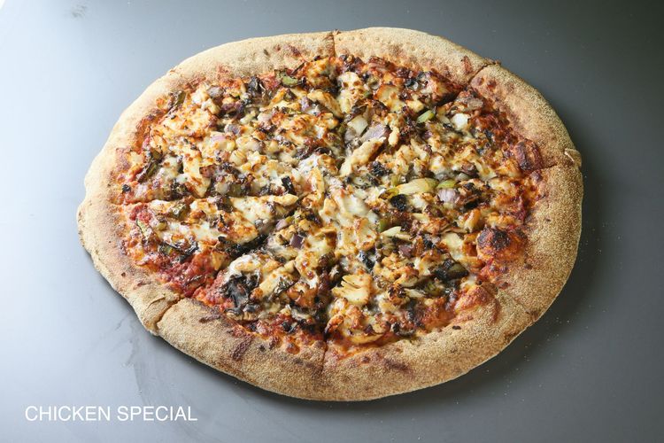 A pizza with four different toppings is sitting on a table.
