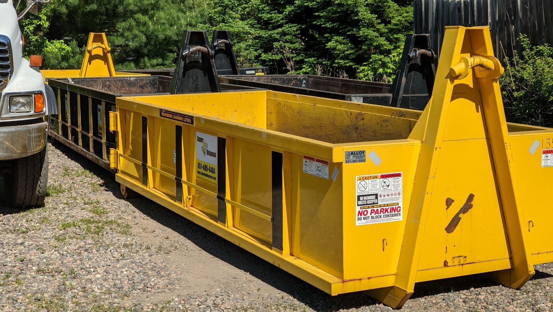 a yellow dumpster has a no parking sign on it