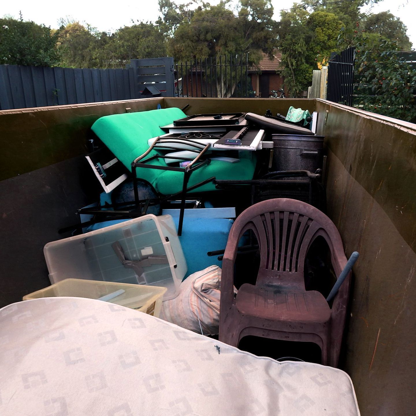 A dumpster filled with furniture and a chair