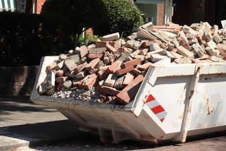 A white dumpster filled with bricks and rocks