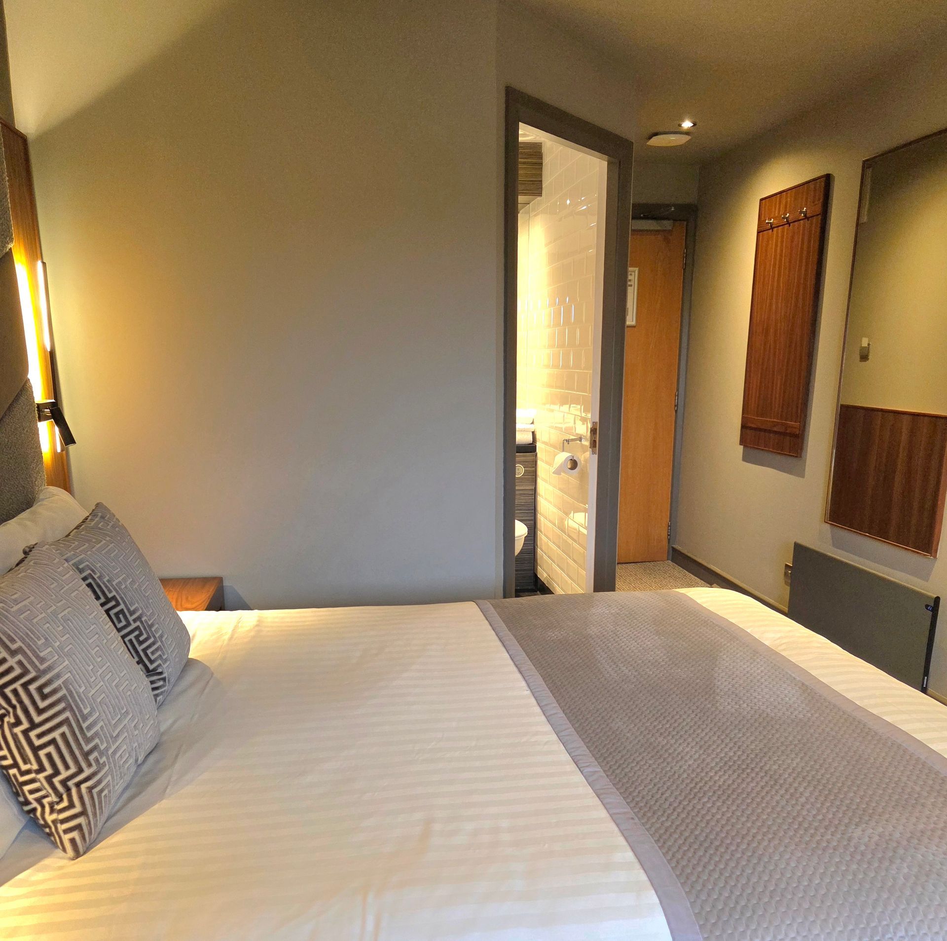 Hotel room coffee station with kettle, cups, tea, and sweeteners on a wooden surface.