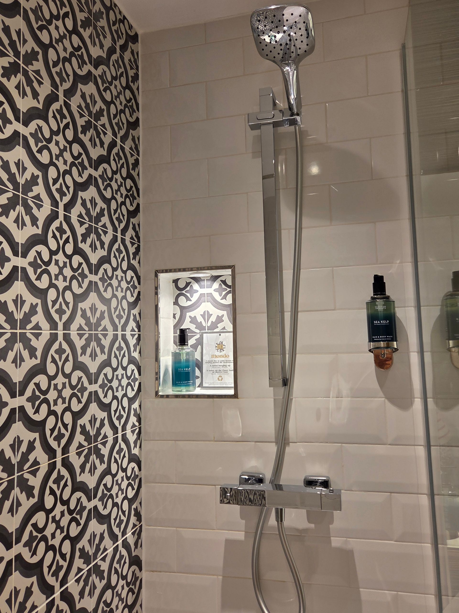 Bathroom with shower stall, white subway tile, patterned glass door, showerhead, and a vanity.