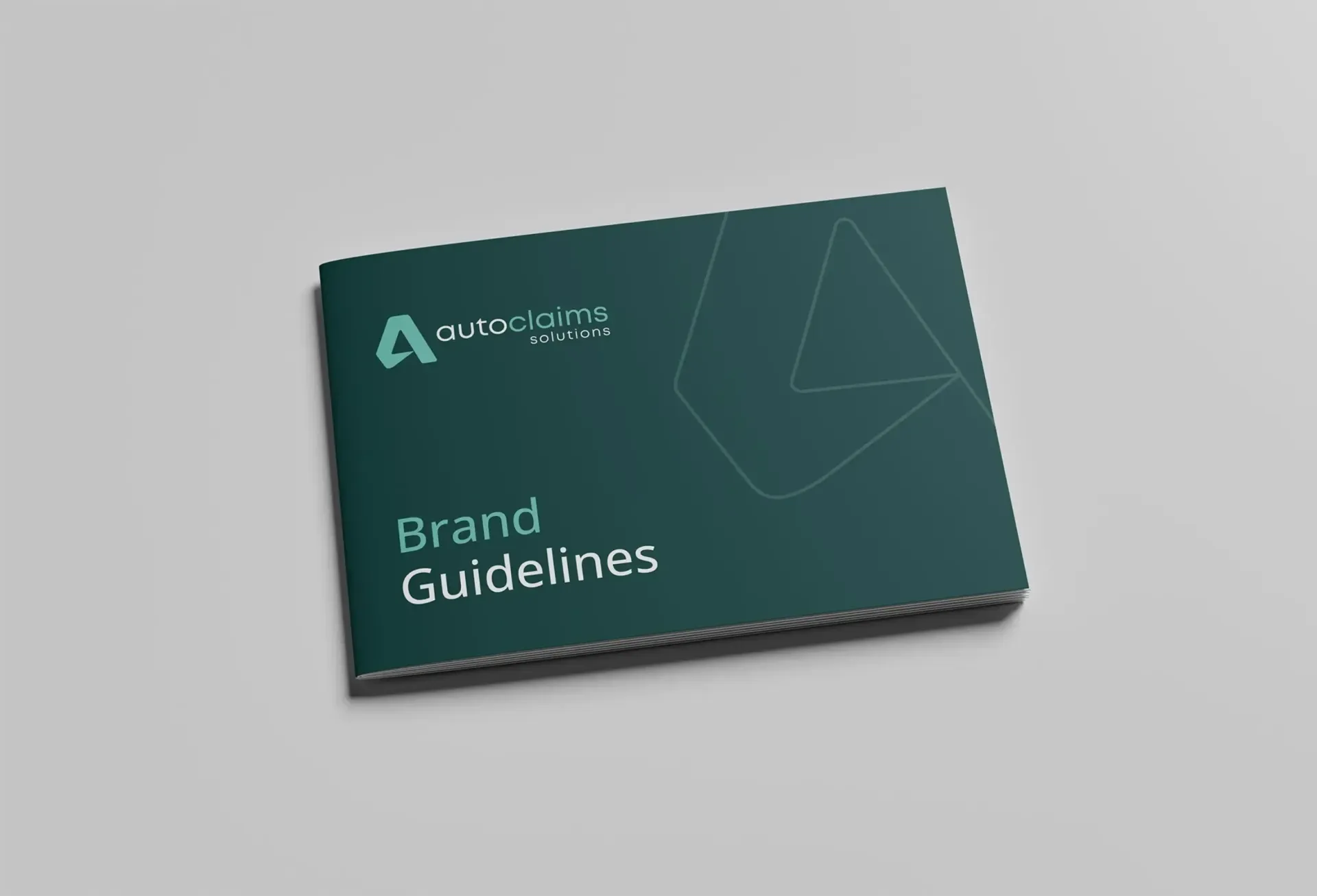 Brand guidelines booklet on a gray surface. Dark teal cover with logo and text 