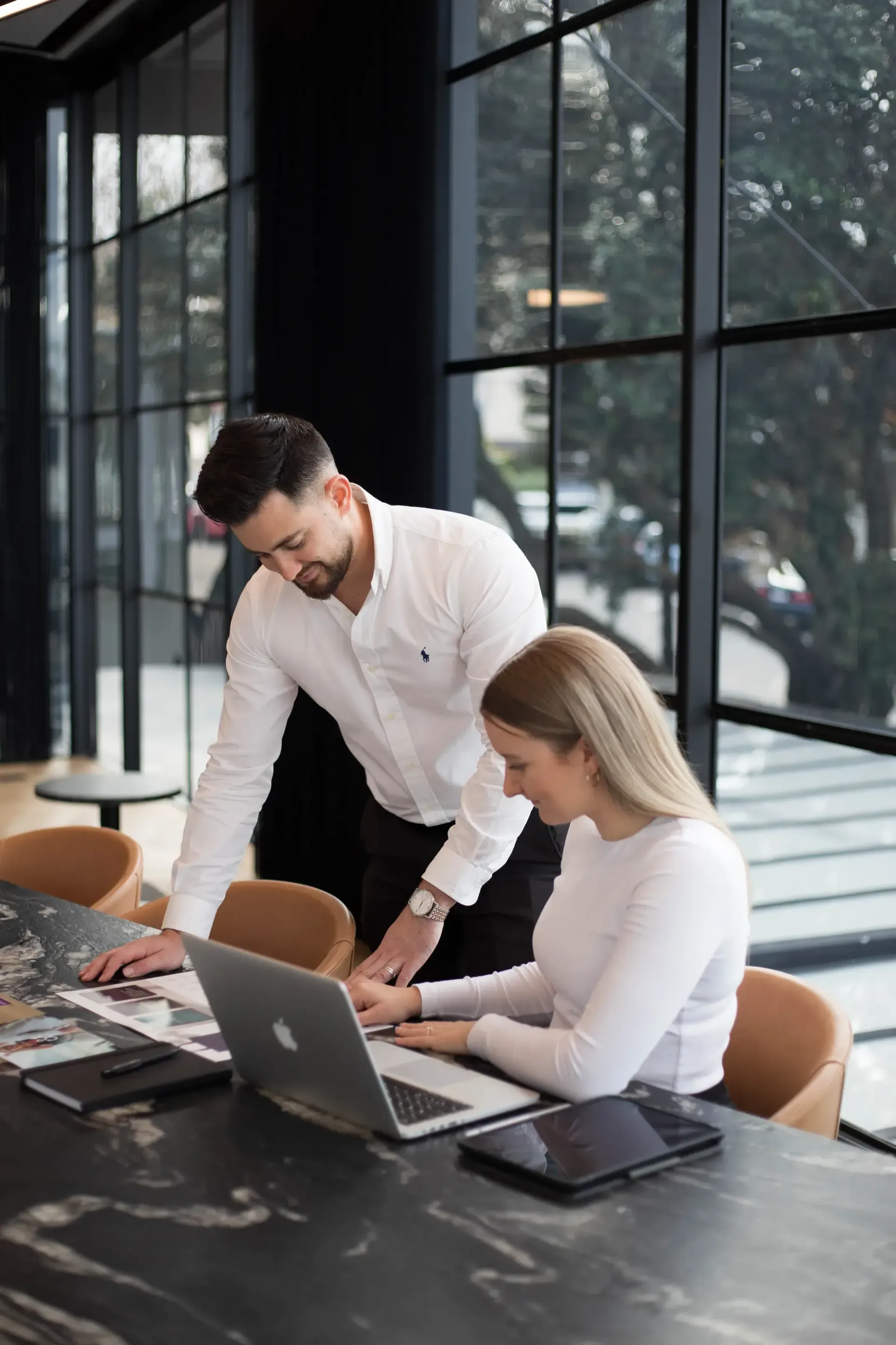 Man and woman looking at a document together at a table, possibly discussing building plans.