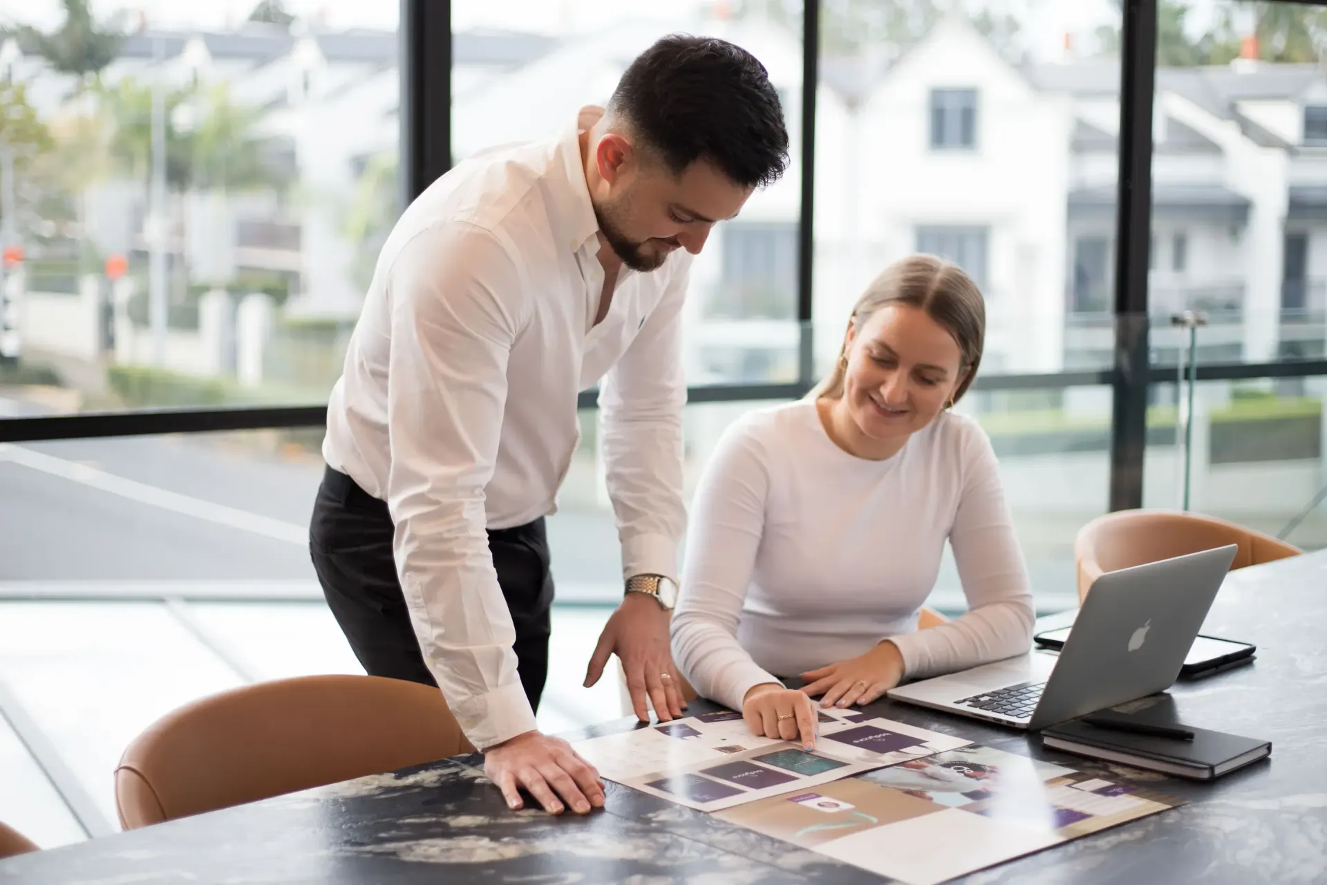 Man and woman looking at a document together at a table, possibly discussing building plans.