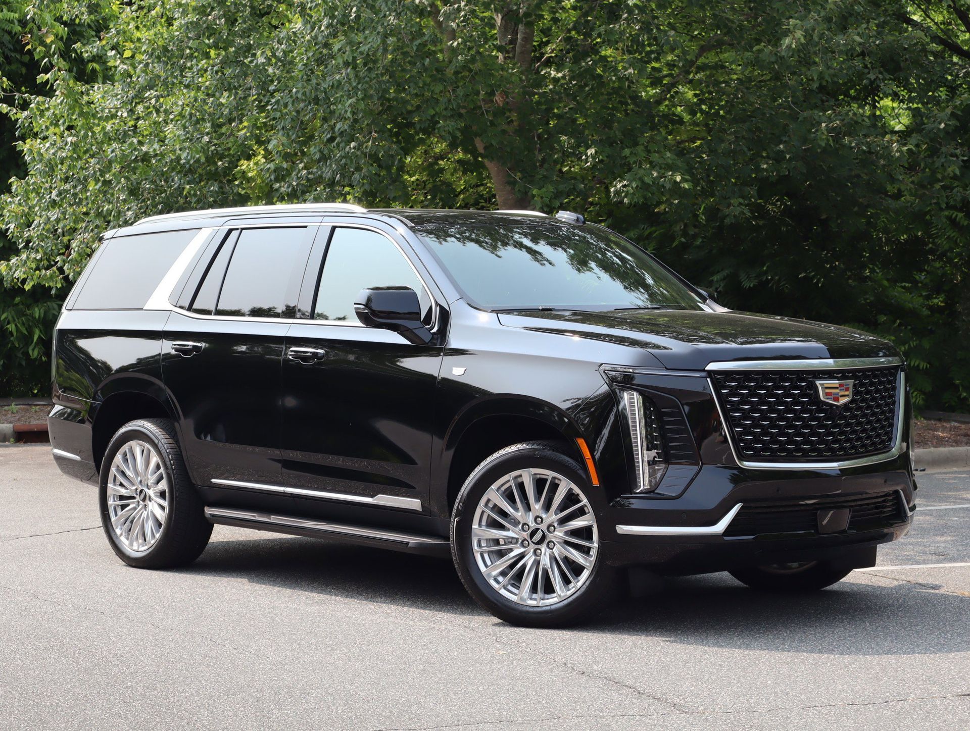 Black Infiniti QX80 SUV parked on a road with a sunset in the background.