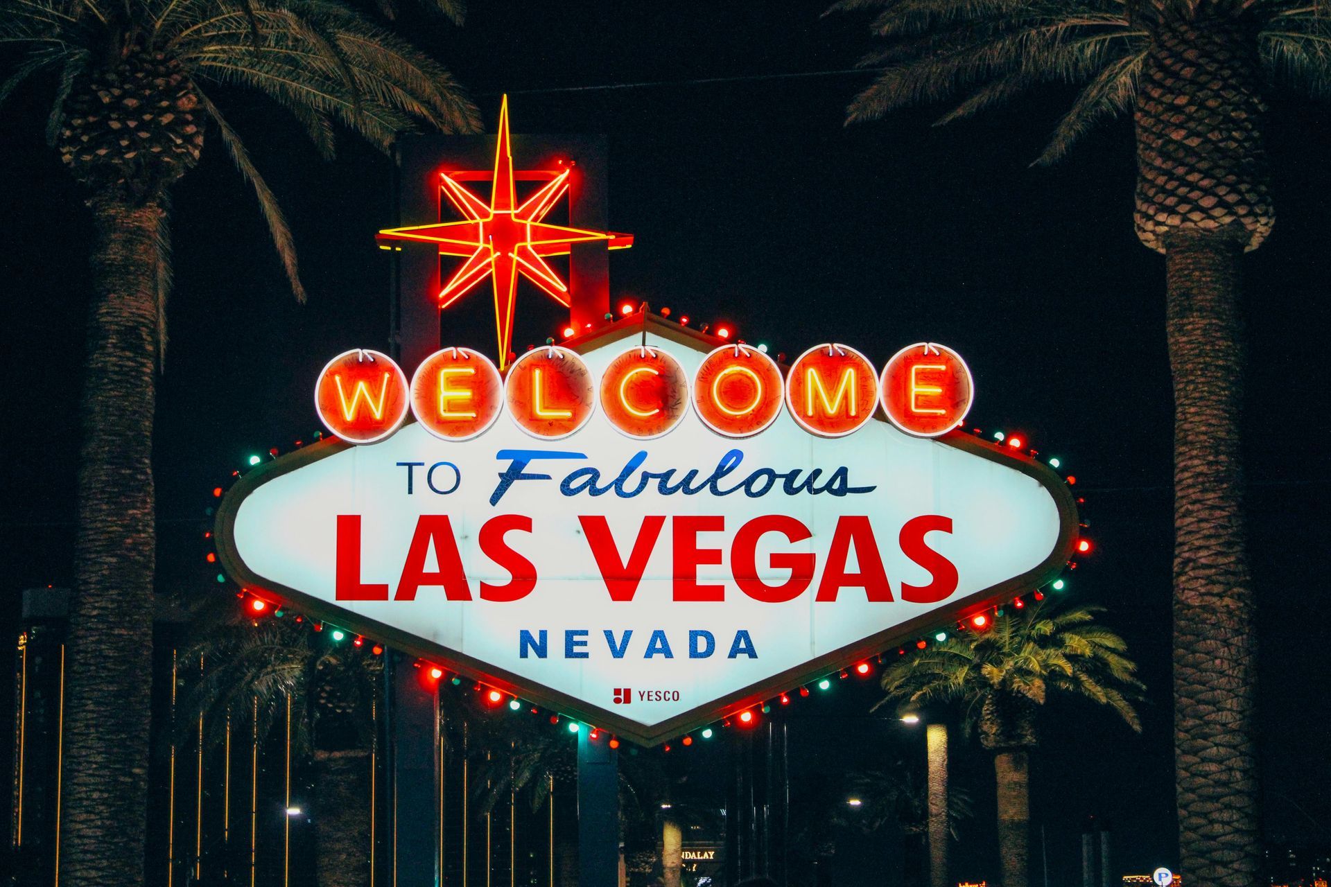 Welcome to Fabulous Las Vegas sign at night, with glowing lights and palm trees.